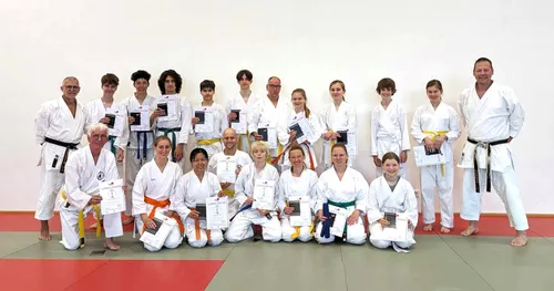 Gruppenbild mit fröhlichen Karatekas mit Urkunden in der Hand